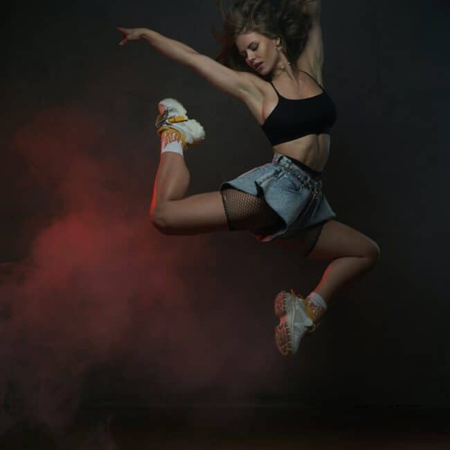 Jumping female dancer in short clothing in dark background