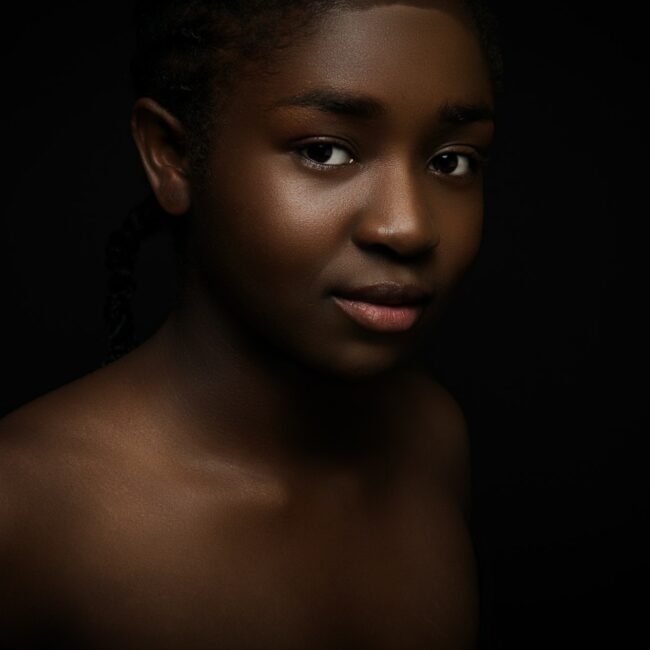 Natural and beautiful woman with dark skin on black bakground