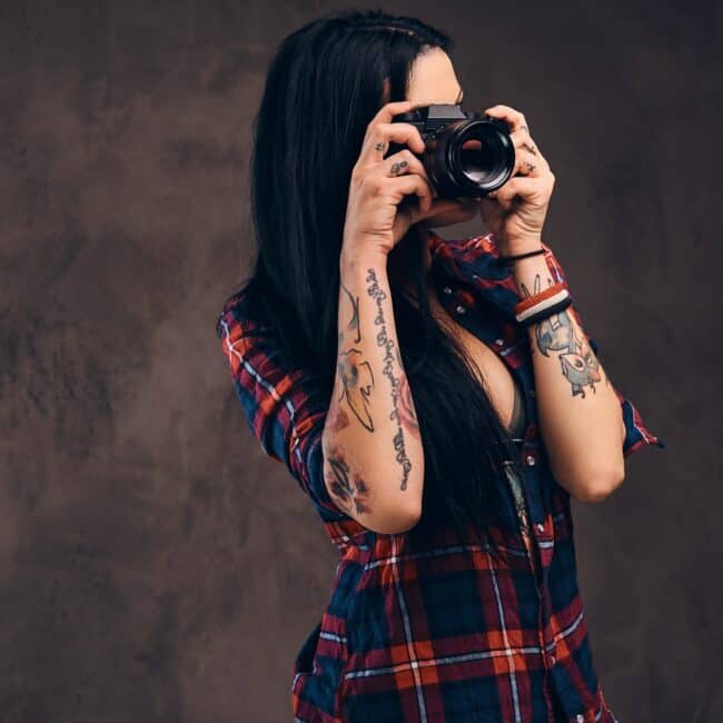 Sexy tattooed hipster girl wearing a red unbuttoned checkered shirt and shorts